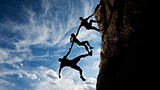 Rock climbers pulling each other up